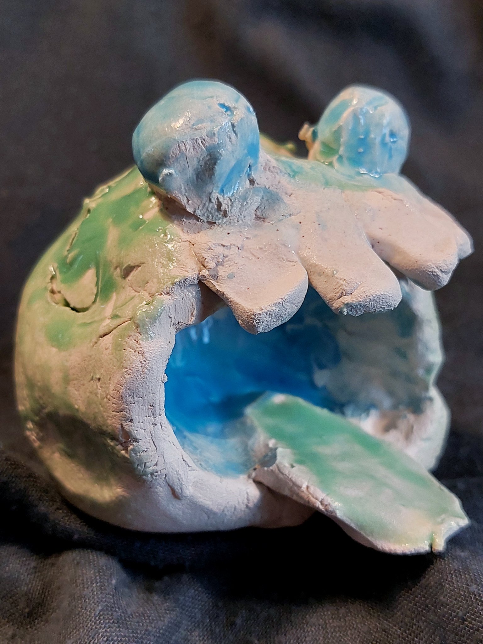 Et keramisk værk fremstillet af et barn forestillende hovedet af et lille, grønt keramikmonster.